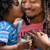 Dad and daughter kiss with steel cup in hand