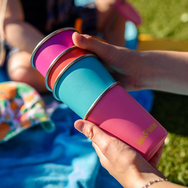 Colorful stackable cups held by a person outdoors