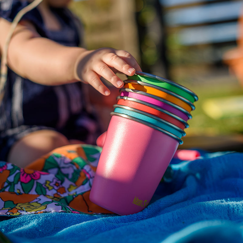 Colorful cups stacked and nested with child reaching for them