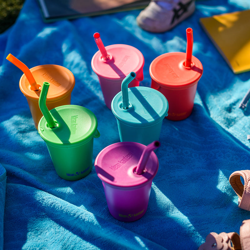 Colorful children's sippy cups with straws on a blue blanket