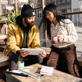 Couple in city drinking from mug and tumbler on patio