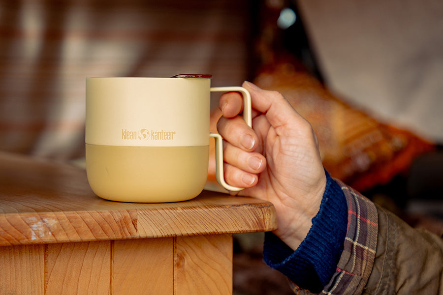 Hand holding a yellow mug on wood table