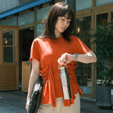 Woman in an orange shirt holding a water bottle outside office