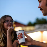 Person holding a 'Santa Cruz' cup while interacting with another person outdoors.