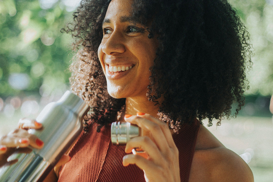 Woman holding a Reflect water bottle with bamboo cap