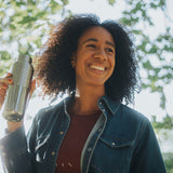 Woman holding a silver water bottle outdoors