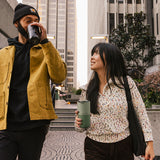 Two people on city street with tumblers