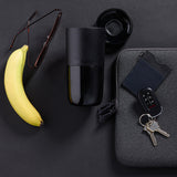 Top view of black tumbler, banana, keys and work stuff on table