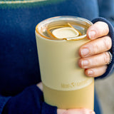 Close up of yellow tumbler with lid in hand