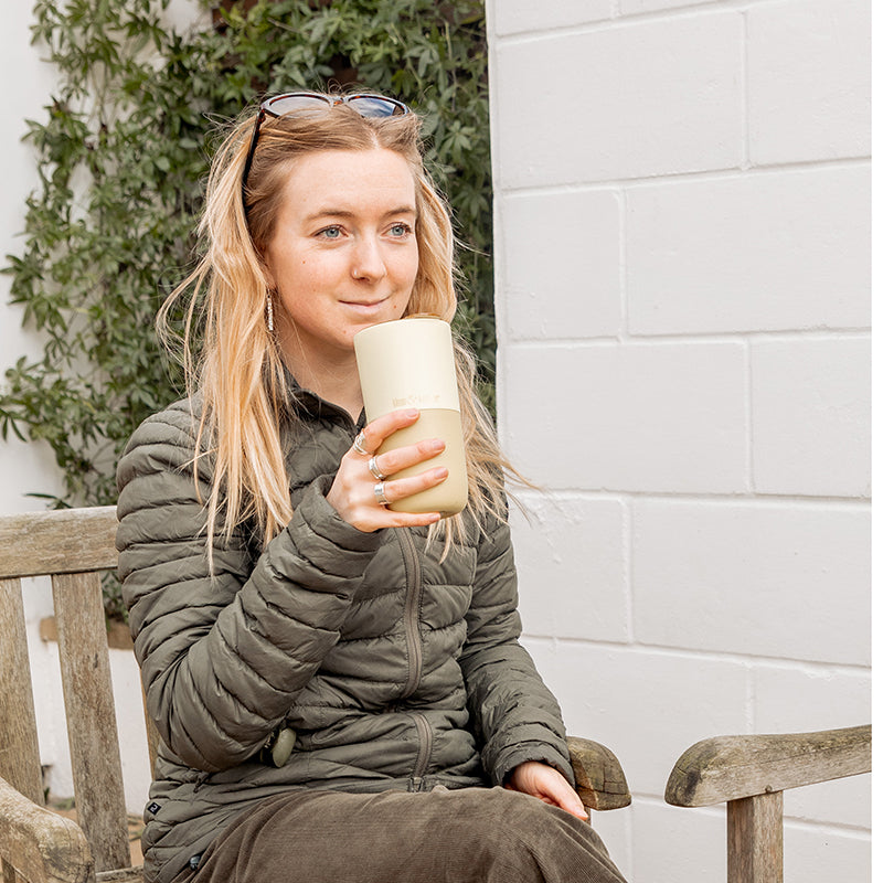 Woman drinking from yellow tumbler and looking out in distance