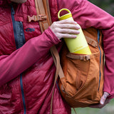 Person holding a yellow water bottle with a backpack