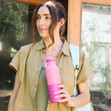 Woman holding a pink water bottle outdoors