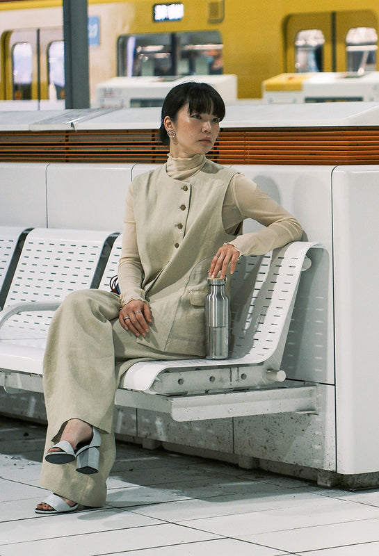 Woman sitting on bench in a train station with Reflect water bottle