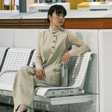 Woman sitting on a bench holding a water bottle waiting for a train