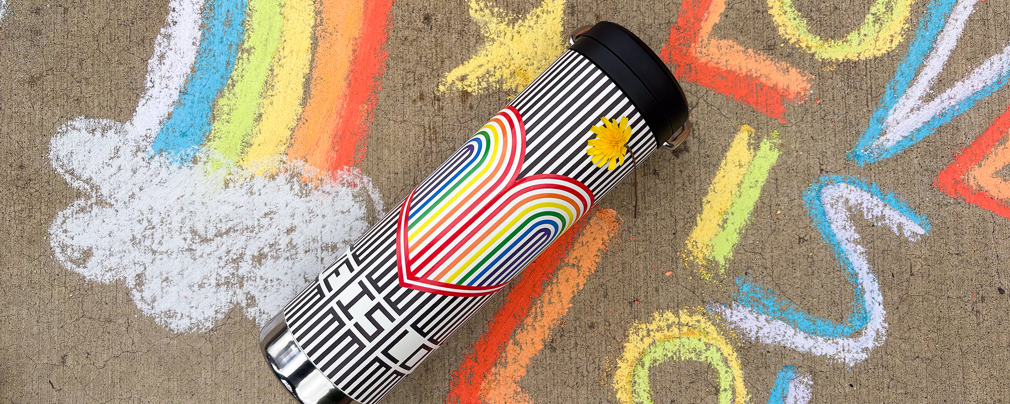 Rainbow hearts water bottle with graphic design on a concrete surface with chalk drawings.