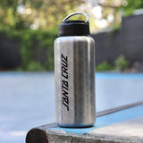 Steel water bottle with 'Santa Cruz' branding on a ledge by a pool.