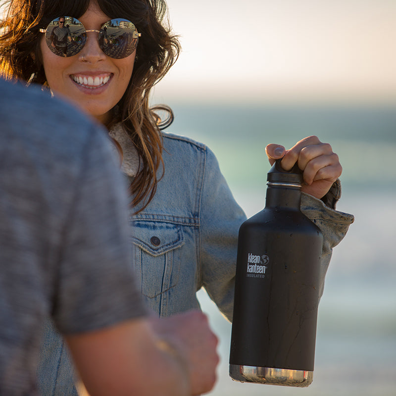 Person holding a black insulated bottle with a scenic background