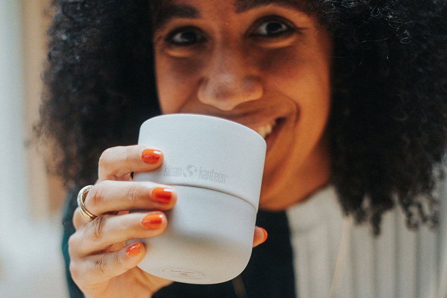 Woman smiling holding a light blue tumbler from Klean Kanteen