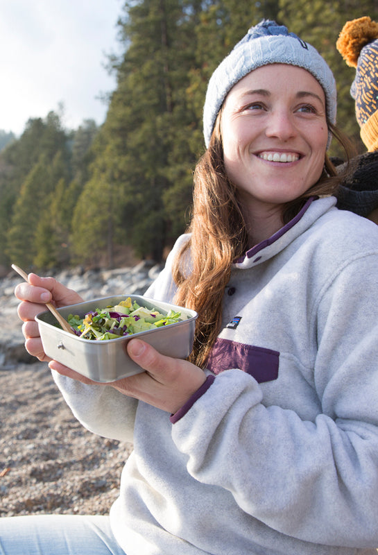 Woman eats salad from a stainless steel food box