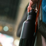 Person holding a black water bottle with a blurred background