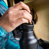Person opening a black water bottle with a blurred background