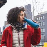Woman drinking from Flip Seal Sport Cap water bottle in city