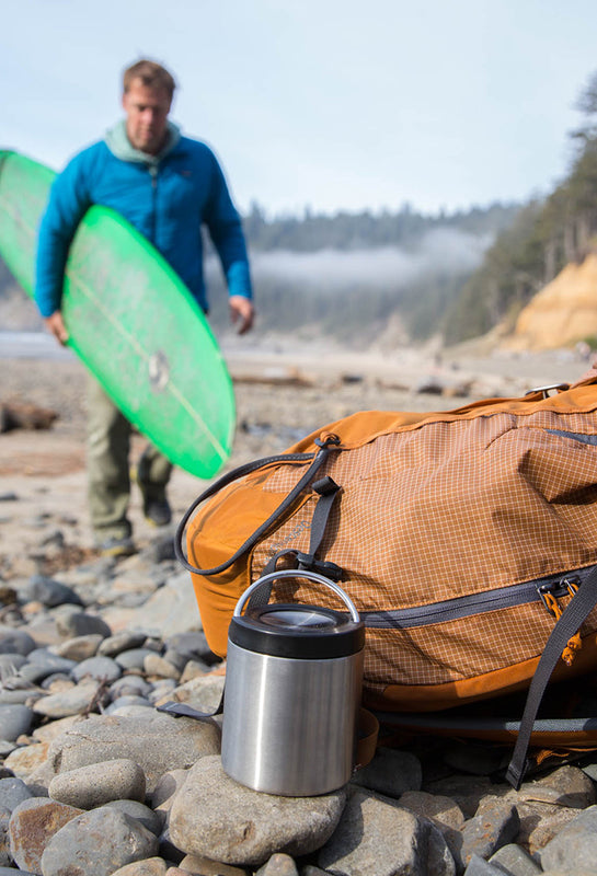 Food canister on beach with surfer