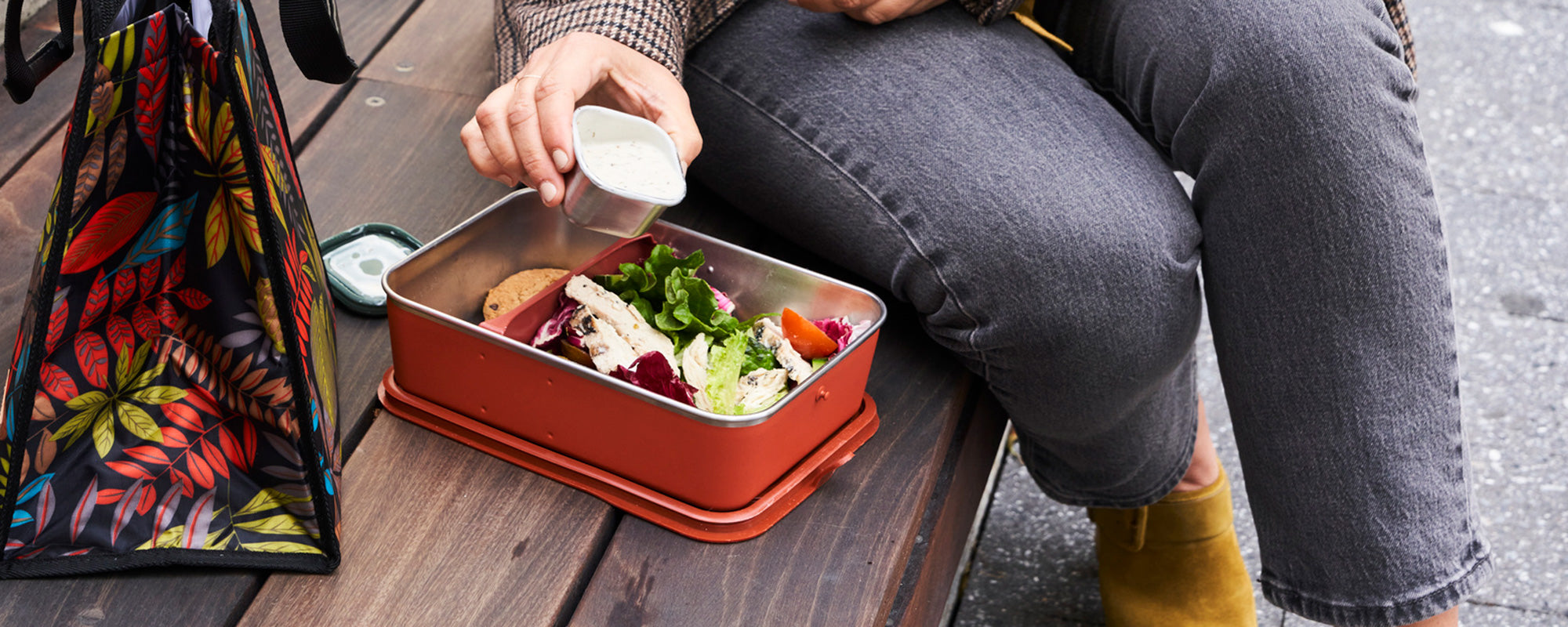 Person preparing a lunch - pouring dressing from food container into lunch box