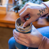 Person holding a blue insulated tumbler twisting cap close