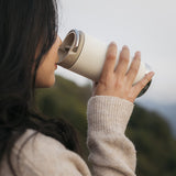 Woman drinking from white insulated mug