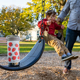 Child on a swing set with a water bottle featuring strawberry design in a park setting