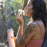 Woman smelling flower with water bottle in hand