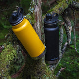 Yellow and black water bottles on a mossy tree branch