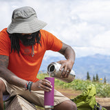 Backpacker refilling water bottle with big half gallon steel bottle