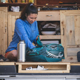 Woman organizing items in a camper van with kitchen cabinets in the back and big steel water bottle
