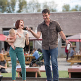 Man and woman playing cornhole with pint cups