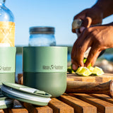 Klean Kanteen cup on a wooden surface with outdoor activity in the background