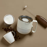 Light blue coffee mug on table with coffee beans and cream
