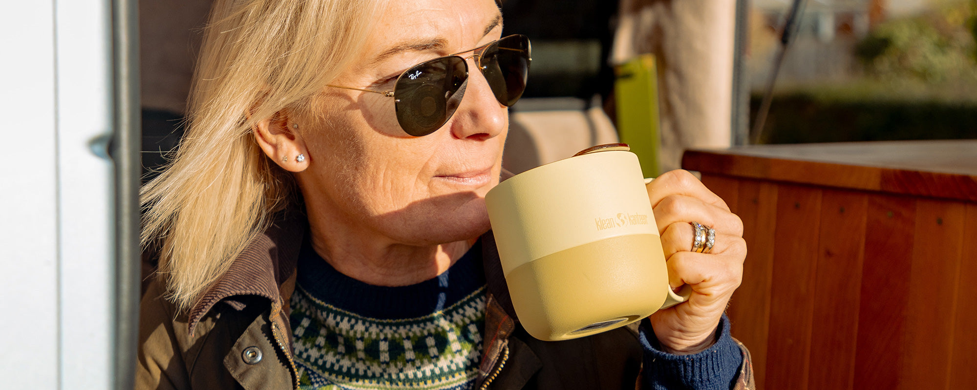 Woman drinking from a yellow mug inside a camper van