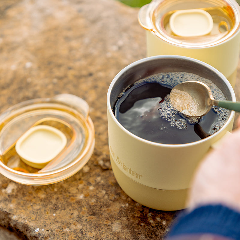 Yellow coffee mug with a spoon, surrounded by similar mugs 