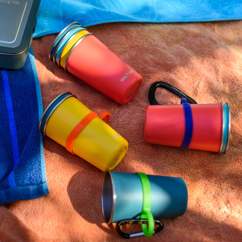 Stack of colorful pint cups with silicone pint rings on a towel