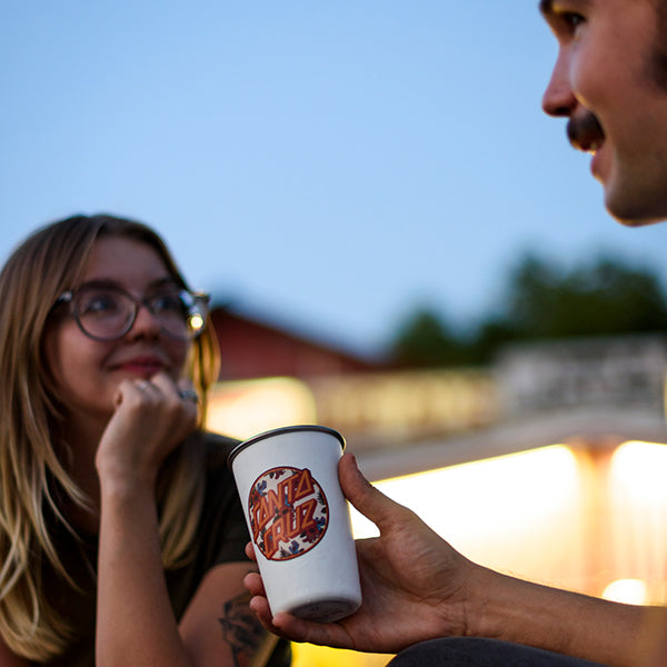 Person holding a 'Santa Cruz' cup while interacting with another person outdoors.
