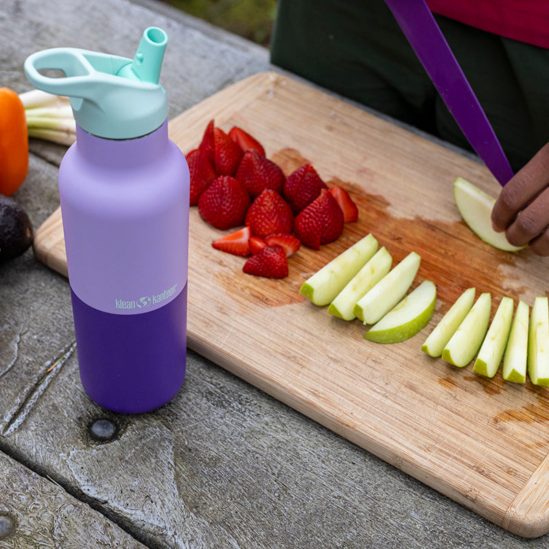 Purple water bottle with fruit on cutting board