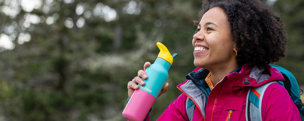 Woman holding a colorful water bottle while hiking 