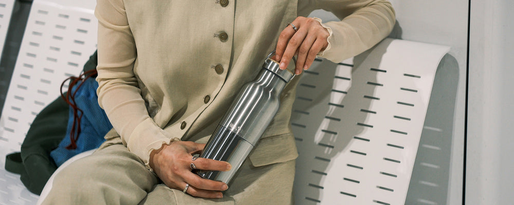 Person holding a Reflect water bottle on bench