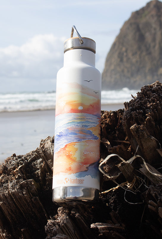 Earth Day Bottle with beach graphic, on beach driftwood stump
