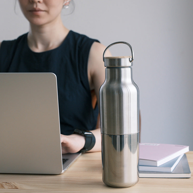 Person using a laptop with a silver water bottle on a desk