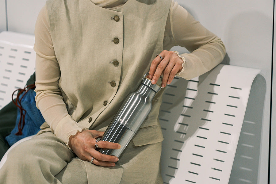Person holding a Reflect water bottle on a bench