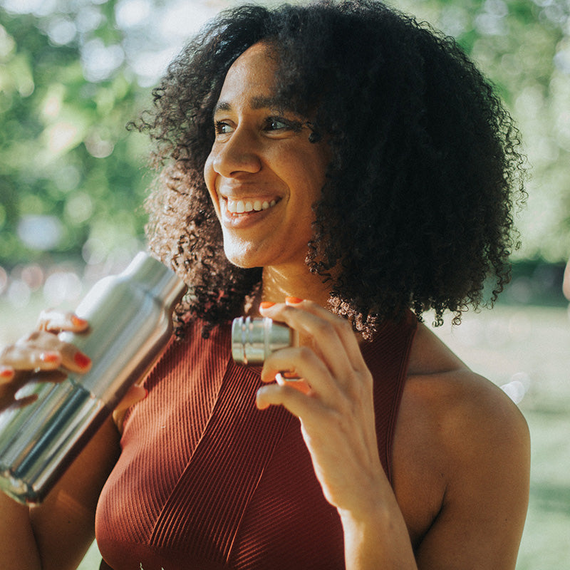 Woman holding a steel water bottle with bamboo cap