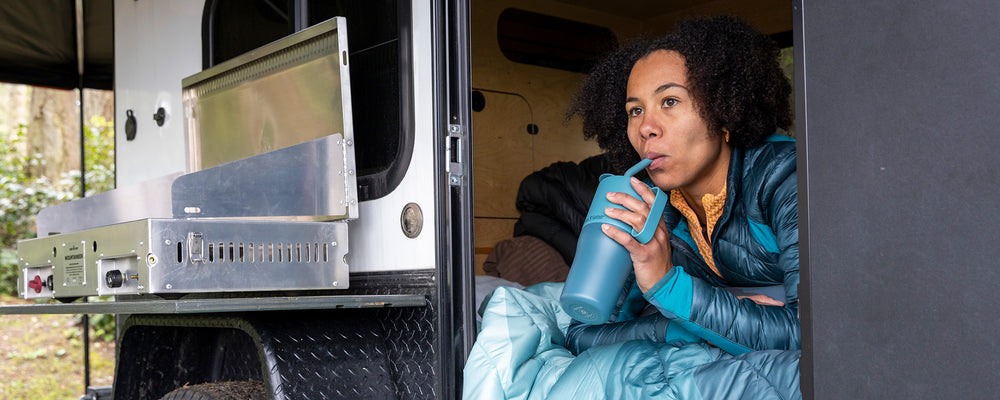 Woman sipping from tumbler inside camper